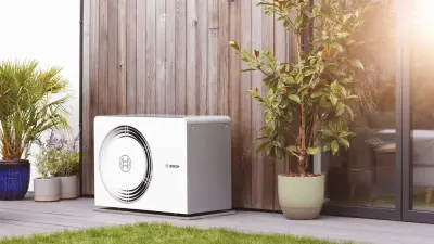 Modern house with green lawn and a heat pump standing next to the wall