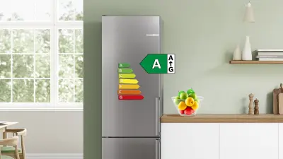 Silver refrigerator with energy efficiency label class A in a modern kitchen.