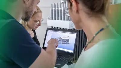 The Bosch PEM electrolysis team in front of a laptop showing a hydrogen production plant