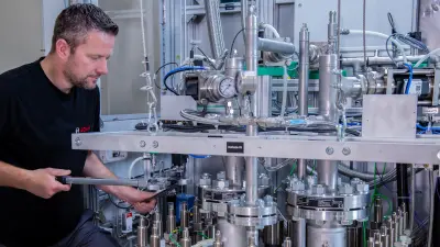 Bosch technician preparing PEM electrolysis stack at test bench, tightening screws for performance testing