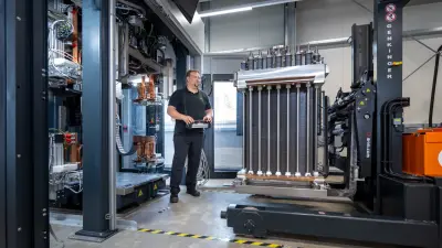 A man operating a remote control to drive the electrolyzer on a forklift into the test station.