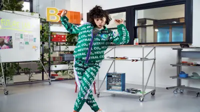 Woman in a suit with Co2-neutral print dancing in a lab